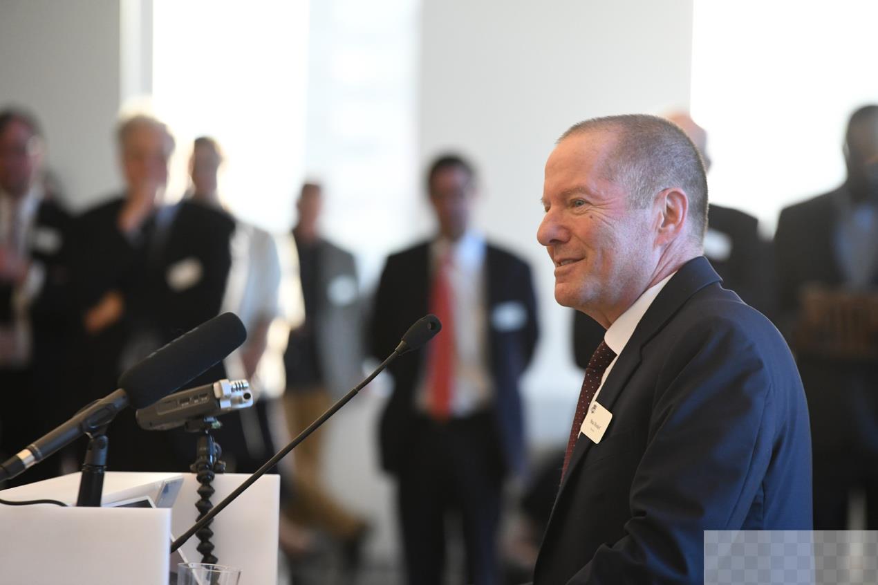 A person in a suit standing at a podiumDescription automatically generated